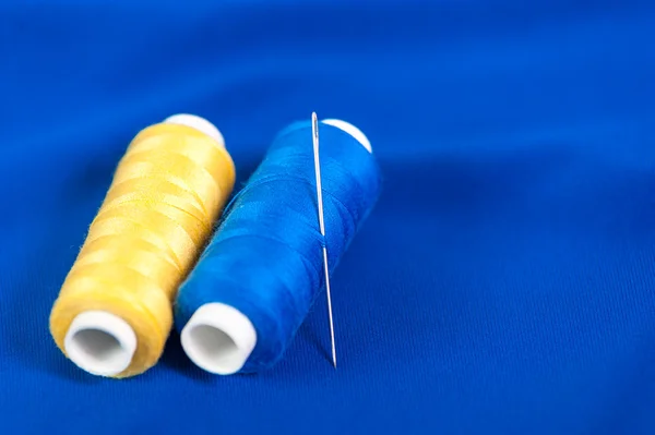 Żółty i niebieski nici z igłą na tekstylne — Zdjęcie stockowe