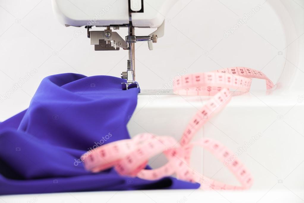 Sewing machine, textile draped and centimeter on a white backgro