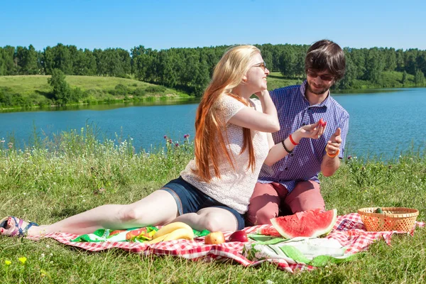 Outdoor portrait of happy loving couple at the lake, which is eating watermelon — Stock Photo, Image