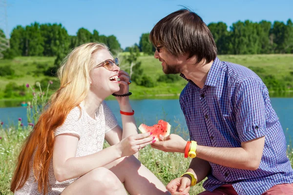 Außenporträt eines glücklichen Liebespaares am See, das Wassermelone isst — Stockfoto