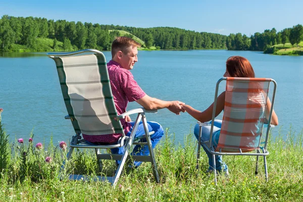 Portrait of a man and woman holding hands, sitting in chairs nea — Stock Photo, Image