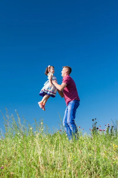 Retrato al aire libre de un padre que arroja a su hija en brazos — Foto de Stock