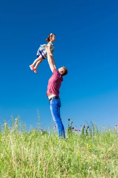 Retrato al aire libre de un padre que lanza a su hija en las manos de nuevo — Foto de Stock