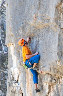 Genç erkek kaya tırmanışçısı uçurumda zorlu bir rotada