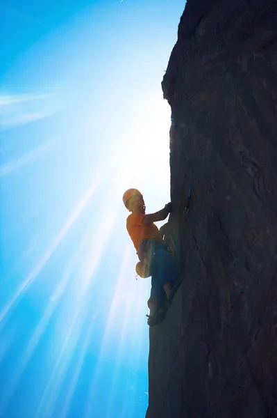 Um alpinista em um penhasco no fundo do céu azul — Fotografia de Stock