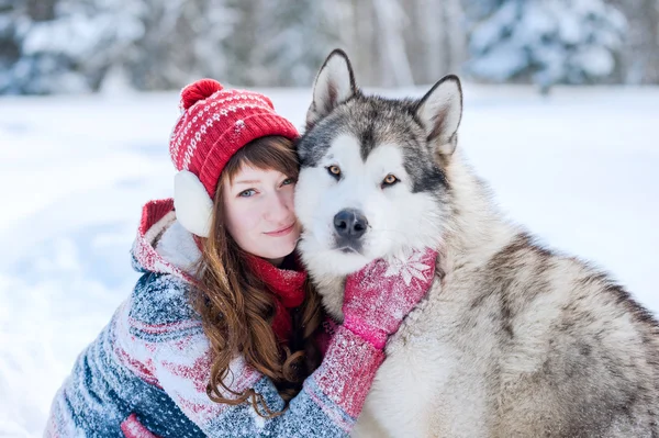 Genç kız bir köpek Husky kış sarılma