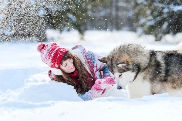 Young girl playing with a dog malamute in the snow in the winter — 스톡 사진
