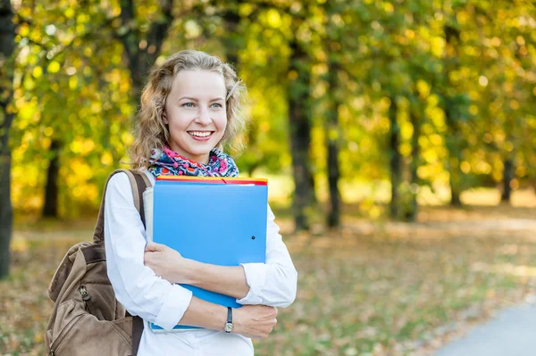 Joyful girl student with folders in the autumn park — Zdjęcie stockowe