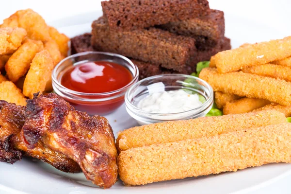 Petiscos quentes variados. Nuggets de frango, queijo torrado, croutons, anéis de cebola com ketchup — Fotografia de Stock