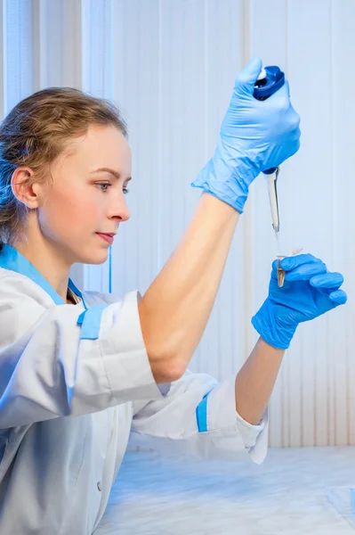 Vrouw wetenschapper doet proeven. In haar handen een pipet en reageerbuizen — Stockfoto