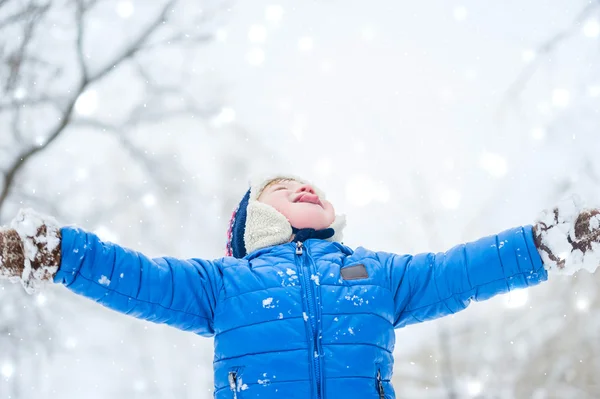 Ritratto all'aperto Felice bambino cattura fiocchi di neve bocca nel parco invernale Fotografia Stock