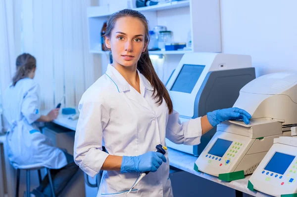 Vrouw onderzoeker scheikundige in een witte lab badjas werken met apparatuur in het moderne laboratorium — Stockfoto