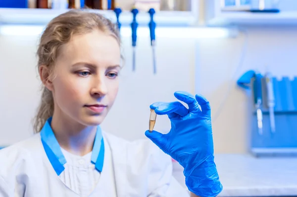 Nő tudós keeped a kezében egy kémcsőbe, és elemzi a modern laboratóriumban — Stock Fotó