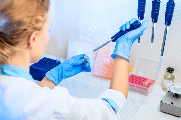 Vrouw arts doet proeven. In haar handen een pipet en reageerbuizen — Stockfoto