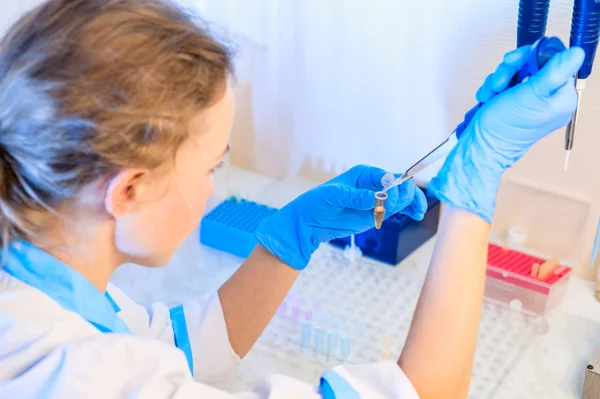 Kadın doktor testler yapıyor. Ona bir pipet ve test tüpleri eller