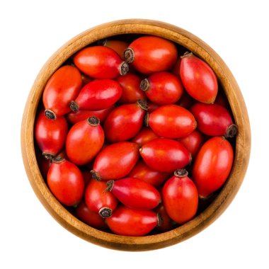 Red rose hips in a wooden bowl over white clipart