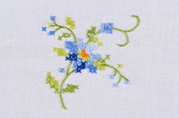 Синій квітковий мотив ручної вишивки на білій лляній скатертині — стокове фото