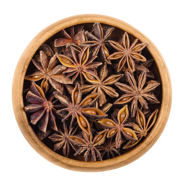 Semi di anice stellato in una ciotola di legno su bianco — Foto Stock