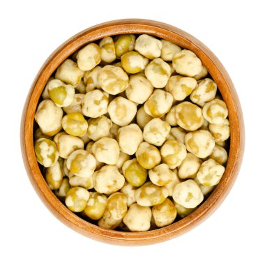 Tahta bir kasede gevrek yeşil bezelyeler. Gevrek mısır nişastası kaplı tuzlu yeşil bezelyeler. Sağlıklı, vejetaryen ve az yağlı atıştırmalık. Yakın plan, yukarıdan izole edilmiş, beyaz arka planda, makro yiyecek fotoğrafı..