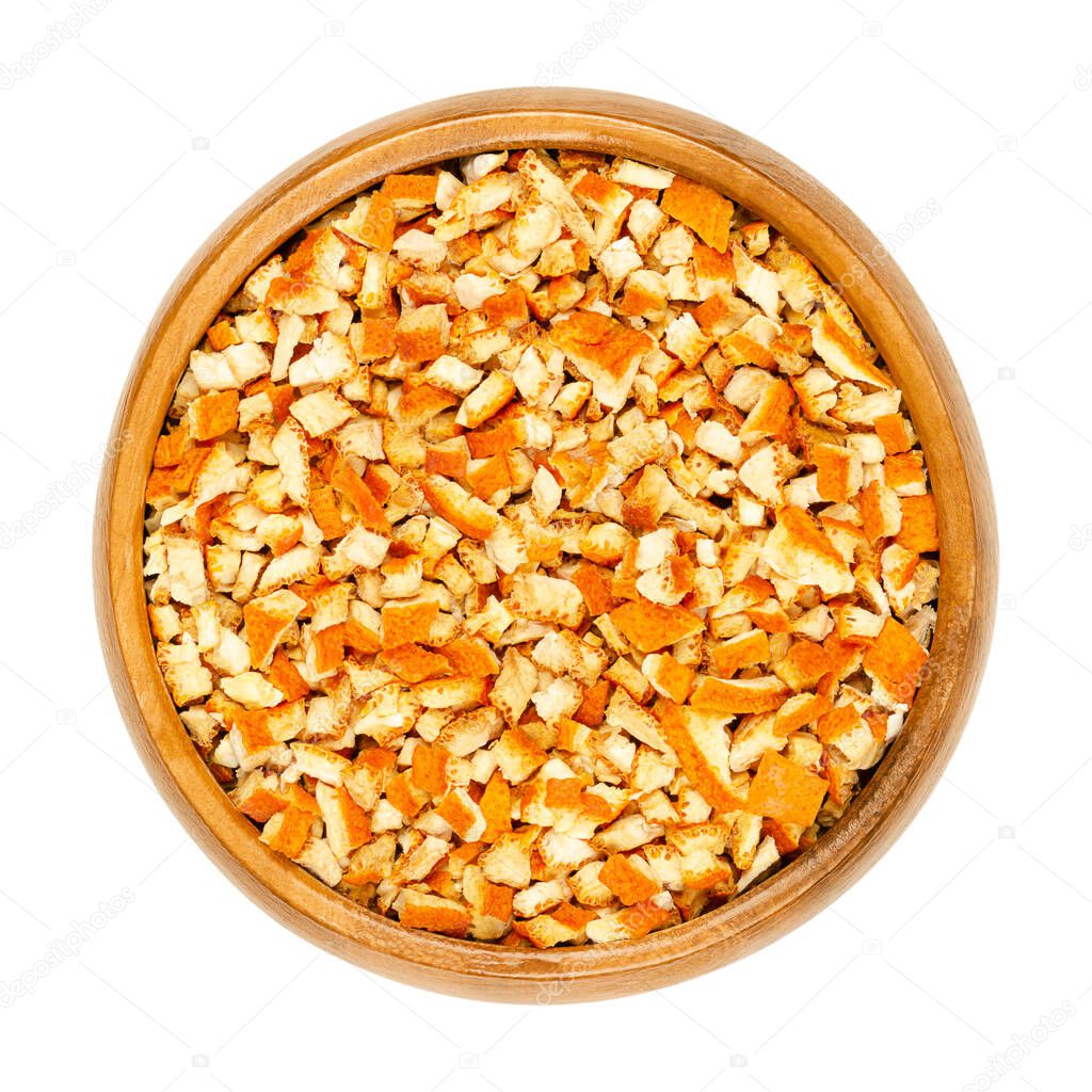 Dried organic orange peel, cut into coarse pieces, in a wooden bowl. Cut skin of organic oranges, used for baking, or for teas. Close-up, from above, isolated on white background, macro food photo.
