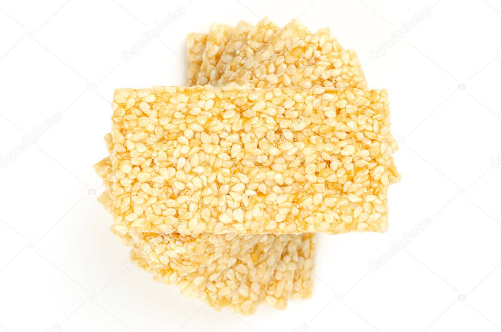 Pile of sesame brittle bars, from above, on white background. Sesame seed candy bars or also crunch, a confection of sesame seeds and honey, pressed into flat bars, a popular snack in the Middle East.