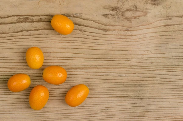 Kumquats ovais na placa velha da madeira do abeto — Fotografia de Stock