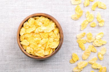 Mısır gevreği ya da ahşap bir kasenin içindeki mısır gevreği, yukarıdan. Mısır veya mısır gevreğinden yapılan kahvaltı gevrekleri. Amerikan diyetinde ve Birleşik Krallık 'ta popüler yiyecekler. Yemek fotoğrafı..