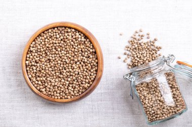 Tam ve kurutulmuş kişniş tohumları, ahşap bir kase içinde keten üzerinde. Baharat olarak kullanılan Coriandrum sativum meyveleri, limon narenciye aromalı, terpenes linalool ve pinene 'den dolayı, kavrulduğunda artar..