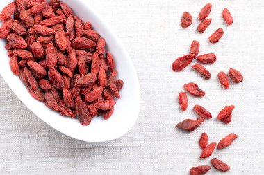 Goji üzümleri, beyaz kase içinde kurutulmuş meyveler. Ayrıca Çin kurt üzümü, kırmızı çarşaf ve evlilik bağı. Parlak, portakal kırmızısı, Lycium barbarının tatlı meyveleri, Çin 'e ve Asya' ya özgü. Fotoğraf.