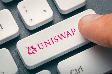 124 numaralı uniswap ile bilgisayar tuşuna basan erkek parmak; uni altcoin logosu. Kripto para birimi madenciliği veya ticaret konsepti.