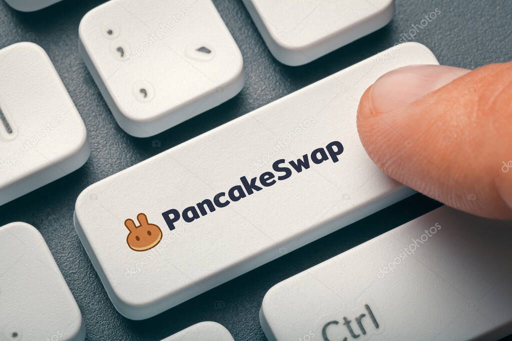 Male finger pressing computer key with pancakeswap altcoin logo.  Cryptocurrrency exchange or trading concept.