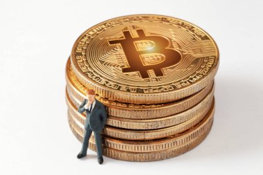 Beyaz arka planda parlayan bitcoin yığınına yaslanırken küçük düşünen bir iş adamı figürü. Bir iş stratejisi geliştiriyorum. Kripto para birimi, engelleme zinciri veya ticaret konsepti.