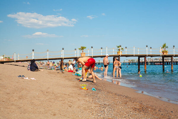 Antalya, Turkey-June 29, 2021: Beach-goers sunbathing, swimming or doing other activites on the beach in summer in Antalya. Antalya a main summer destination for Russian, Ukrainian, British, Polish and Germans tourists.