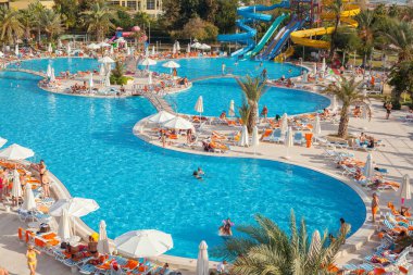 Antalya, Türkiye-18 Ekim 2013: İnsanlar yüzme havuzunda yüzüyor, güneşleniyor ve bir yaz öğleden sonra otelde başka aktiviteler yapıyorlar. Antalya, Rus, Ukraynalı, İngiliz, Polonyalı ve Alman turistler için başlıca bir yaz merkezi..