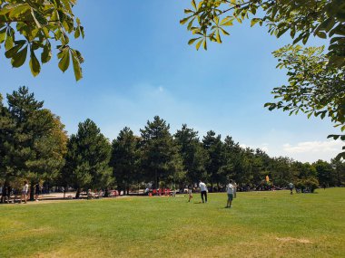 Ankara, Türkiye-15 Ağustos 2021: Ankara, Türkiye 'deki Ahlatlibel Park' ta güneşli bir yaz gününde yerel halk iyi vakit geçiriyor. Uçurtma uçuran adam, futbol oynayan çocuk ve çayırda konuşan insanlar..