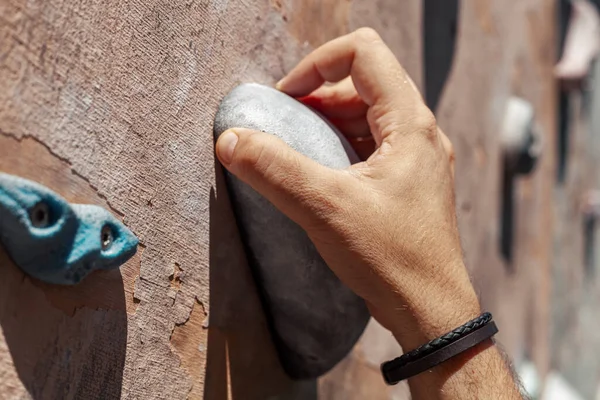 男性の手グリップクライミングのクローズアップ写真は 着用した壁の外に保持しています 公園で人工岩登りの壁でボルダリング運動をしている男 — ストック写真