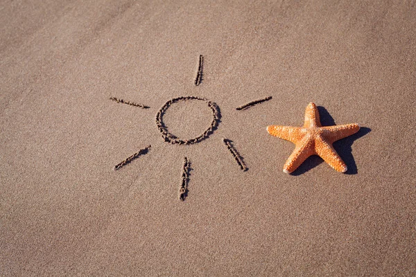 Big orange starfish and sun drawing on sheashore — Stock Photo, Image