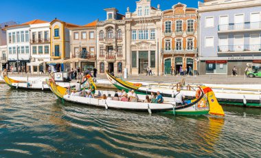 AVEIRO-PORTUGAL: 13 Ekim 2025: Portekiz 'in merkezi kanalı boyunca gezginleri taşıyan iki geleneksel moliceiro goncası, pastel renkli Art Nouveau ve tarihi yapılara karşı hazırlanmıştır..