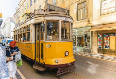 LISBON-PORTUGAL: 05 Ekim 2025: Güneşli bir günde Lizbon, Portekiz 'in tarihi caddelerinde seyahat eden klasik klasik vintage tramvay. İkonik tramvay kullanımı turistler arasında çok popüler bir ulaşım biçimidir..