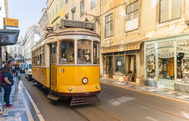 LISBON-PORTUGAL: 05 Ekim 2025: Güneşli bir günde Lizbon, Portekiz 'in tarihi caddelerinde seyahat eden klasik klasik vintage tramvay. İkonik tramvay kullanımı turistler arasında çok popüler bir ulaşım biçimidir..