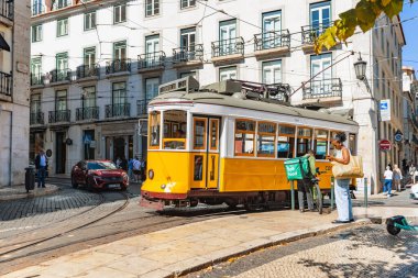 Lizbon 'un tarihi caddelerinde seyahat eden ikonik klasik sarı tramvay 05 Ekim 2025. İkonik tramvay kullanımı turistler arasında çok popüler bir ulaşım biçimidir..