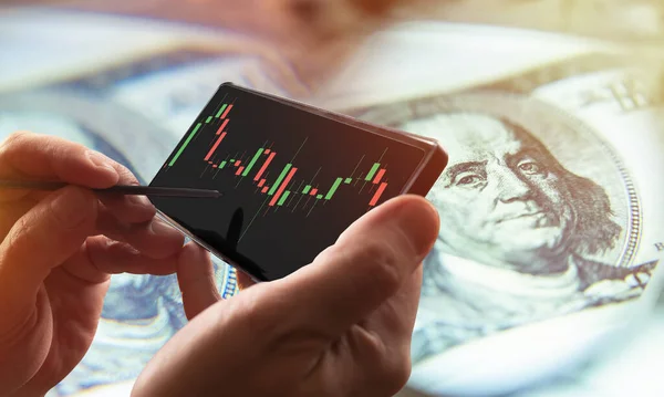 Trade. Analysis of exchange information. Profit from exchange operations. Bidding on the Internet. A person studies the chart of changes in quotes on a smartphone. Stock analysis. Exchange strategies.