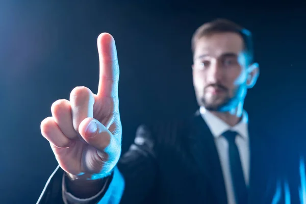 Appropriate option selection.The man taps the touch panel with his finger. The hand of a man with an outstretched index finger on the background of a blurry portrait of a businessman.