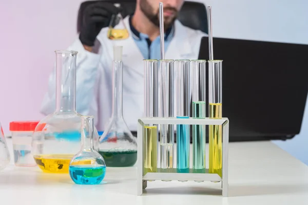 Laboratory glassware on the table. Laboratory glassware next to researcher. A man in a white coat in the background. Concept - sale of Lab glassware. Glass vials on the laboratory bench.