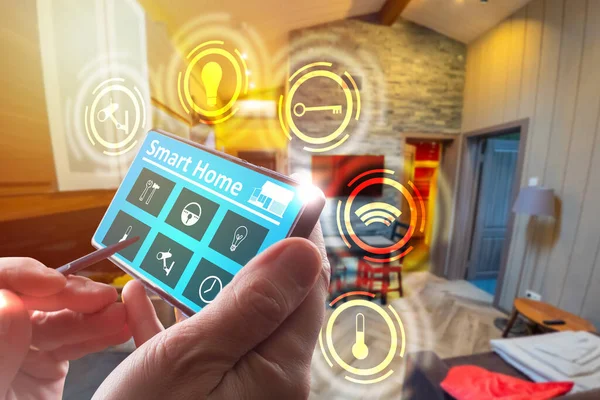 Smart home logo on smartphone screen. concept - control a smart home through an application on phone. Phone is in hands of a man. smart home automation. Blurred living room in background.