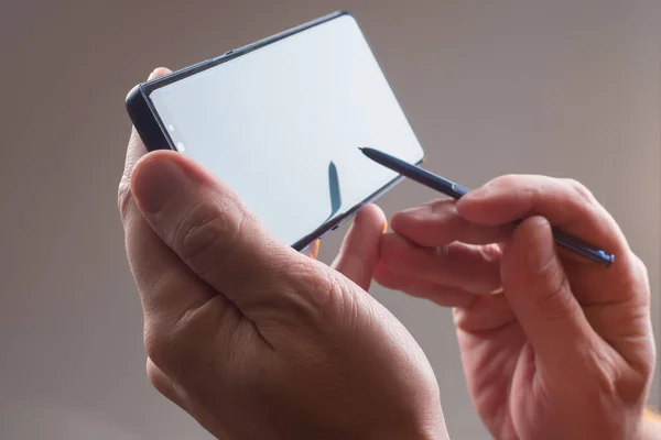 Smartphone screen in hands. Hands with a phone close-up. Man shows what is happening on the screen. Concept - demonstration of the application on phone. Hands with a phone on a dark background. App