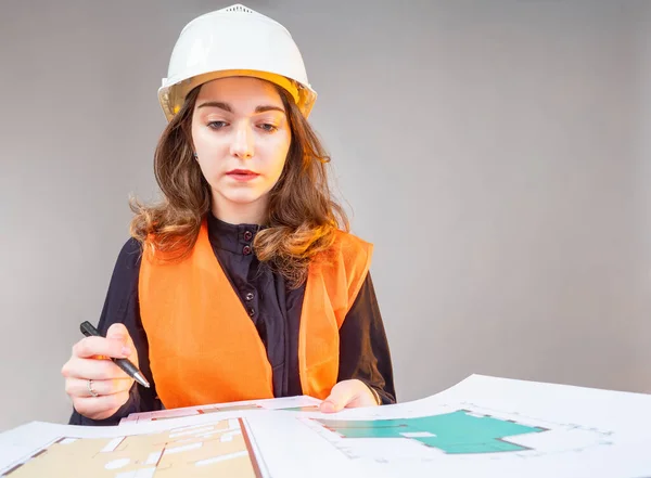 Girl holds construction drawings. Student works with drawings. Concept - girl studying for an architect. Woman in a builder uniform. Building plans on paper. Concept - female construction team leader