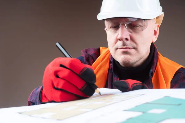 Redevelopment. Man draws on drawings. Builder corrects construction drawings. Man makes notes on the plan of apartment. Concept - builder edits a floor plan. Concept- services of construction company