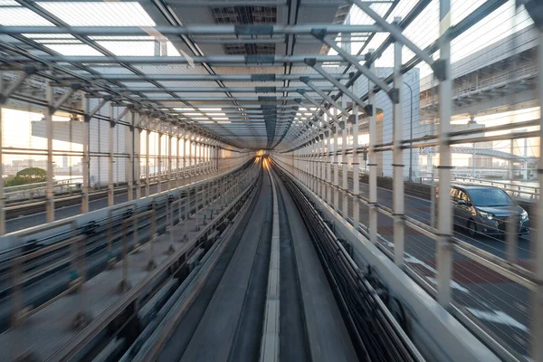 Japan. The transport system of Tokyo. Road and rail links in the Japanese capital. Special corridor for trains.The car is moving near the railway tracks in Tokyo. Different types of transport in Tokyo