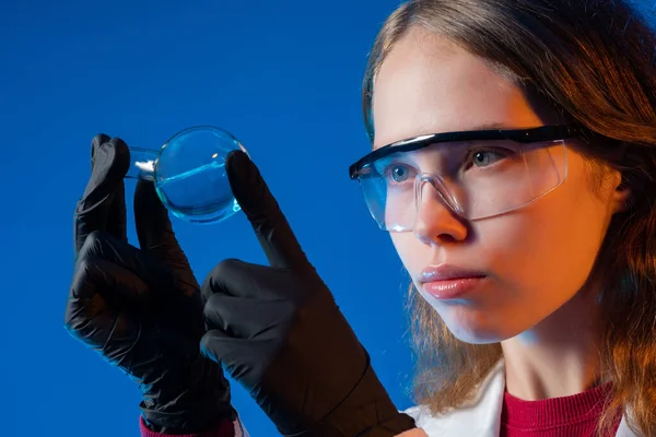 Laboratory student with a test tube in his hands. Chemist student is holding small test tube. laboratory student on a blue background. Portrait of young chemist in laboratory. Training in lab. Study